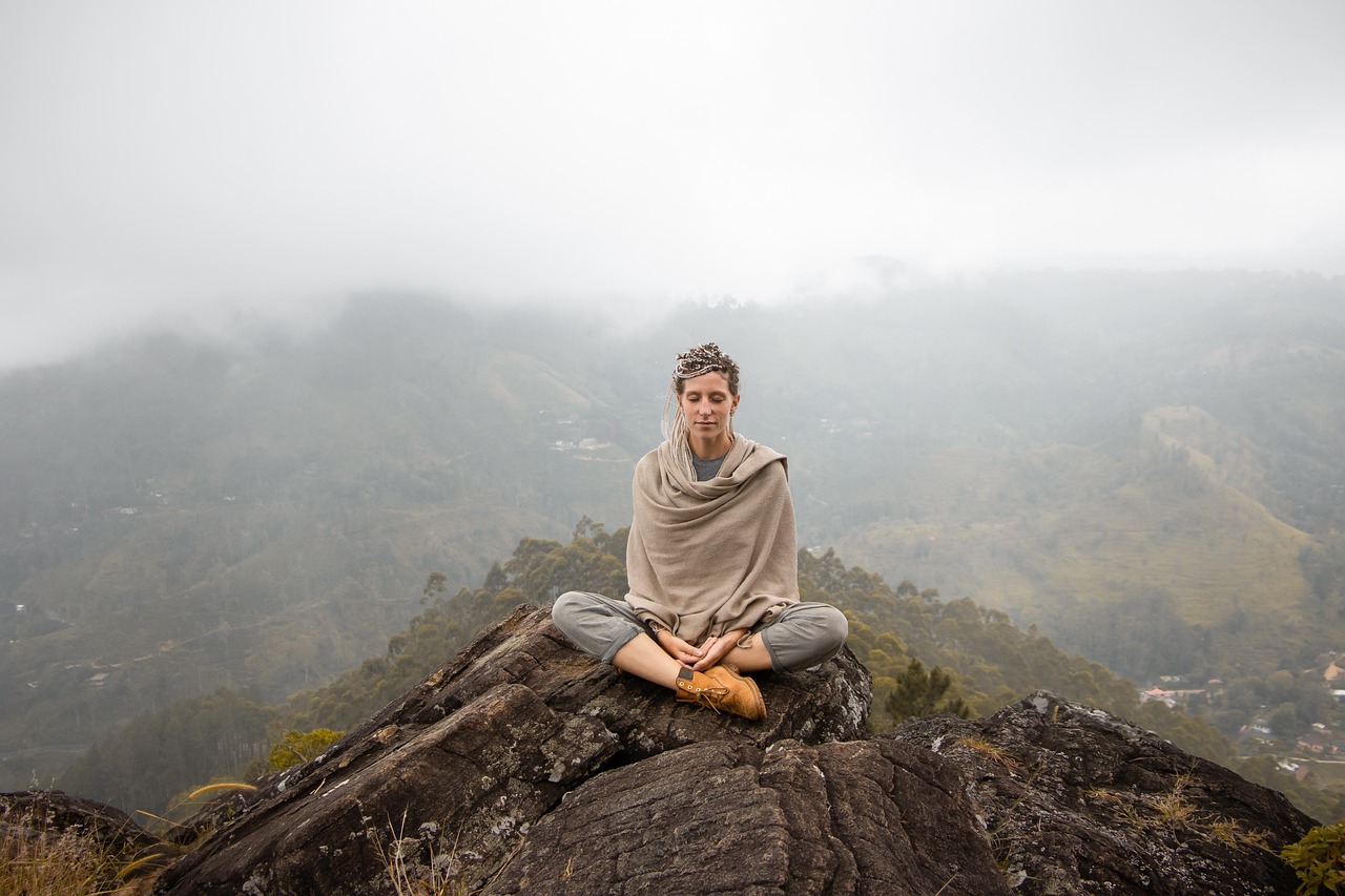 Femme pratiquant le yoga dans un champ verdoyant avec vue sur les montagnes du Queyras.